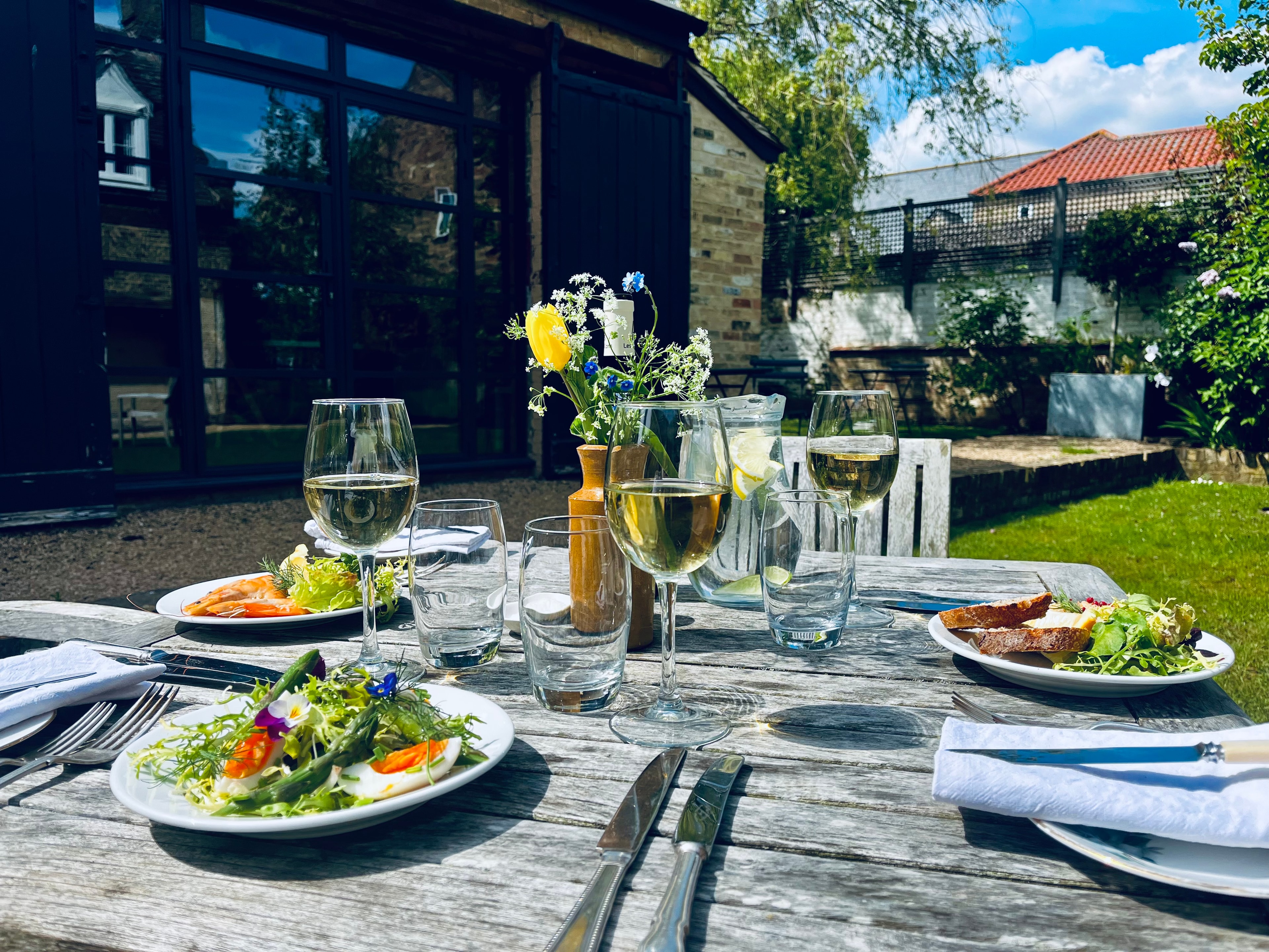 Summer garden table set for lunch with wine and salads